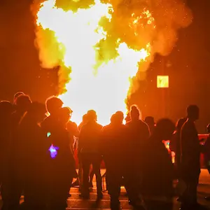 Students stand around a large bonfire