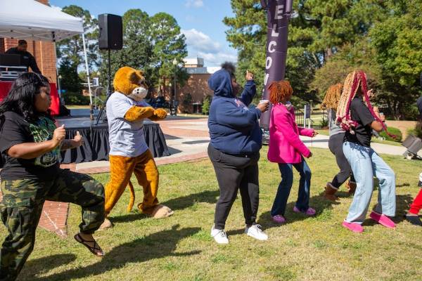 Several students dancing with Cody the Cougar