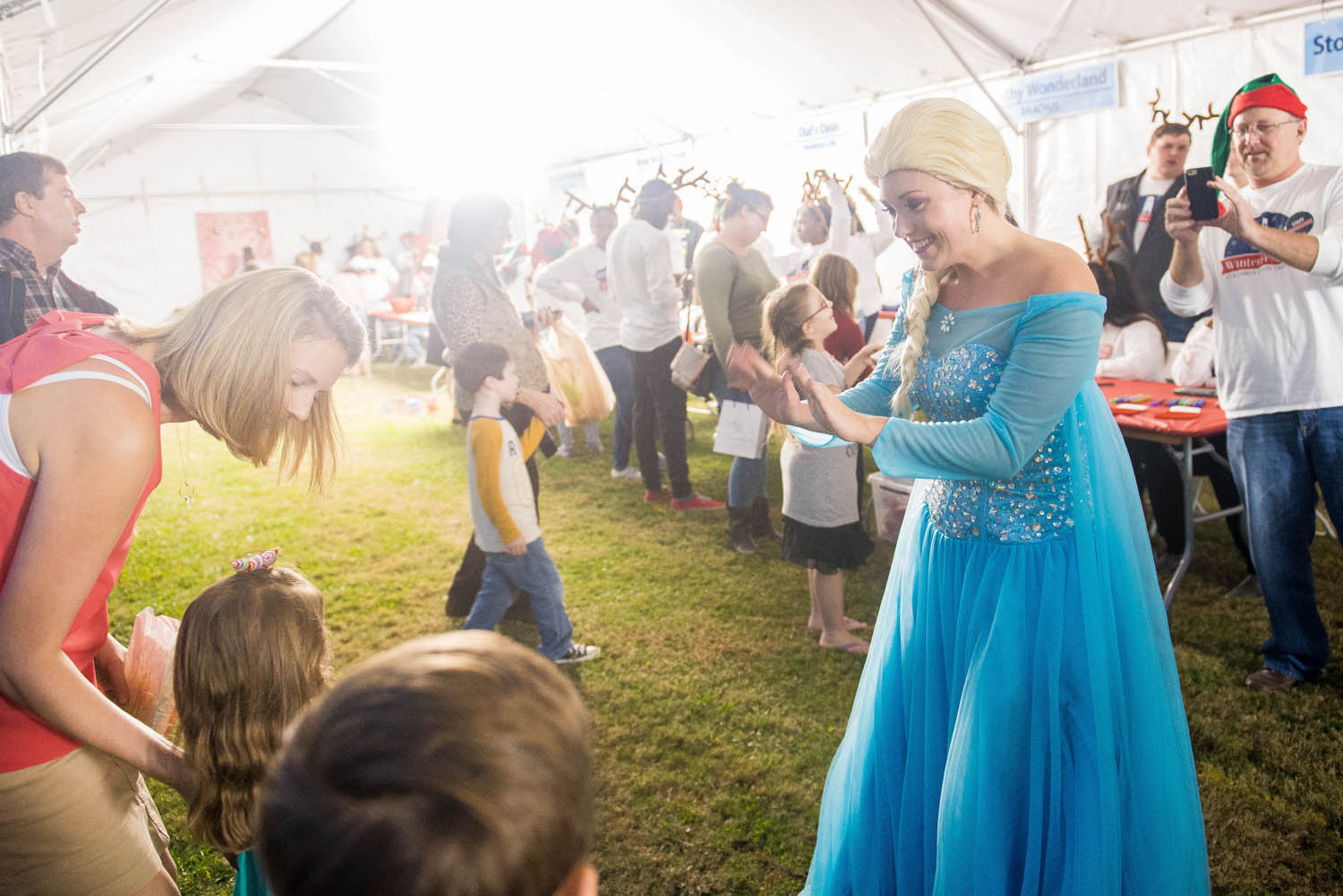 a woman in a blue dress waving at children